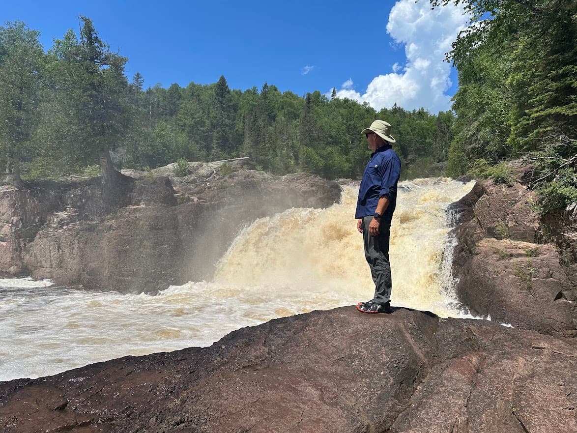 Robert Trupe standing calmly beside a rushing waterfall